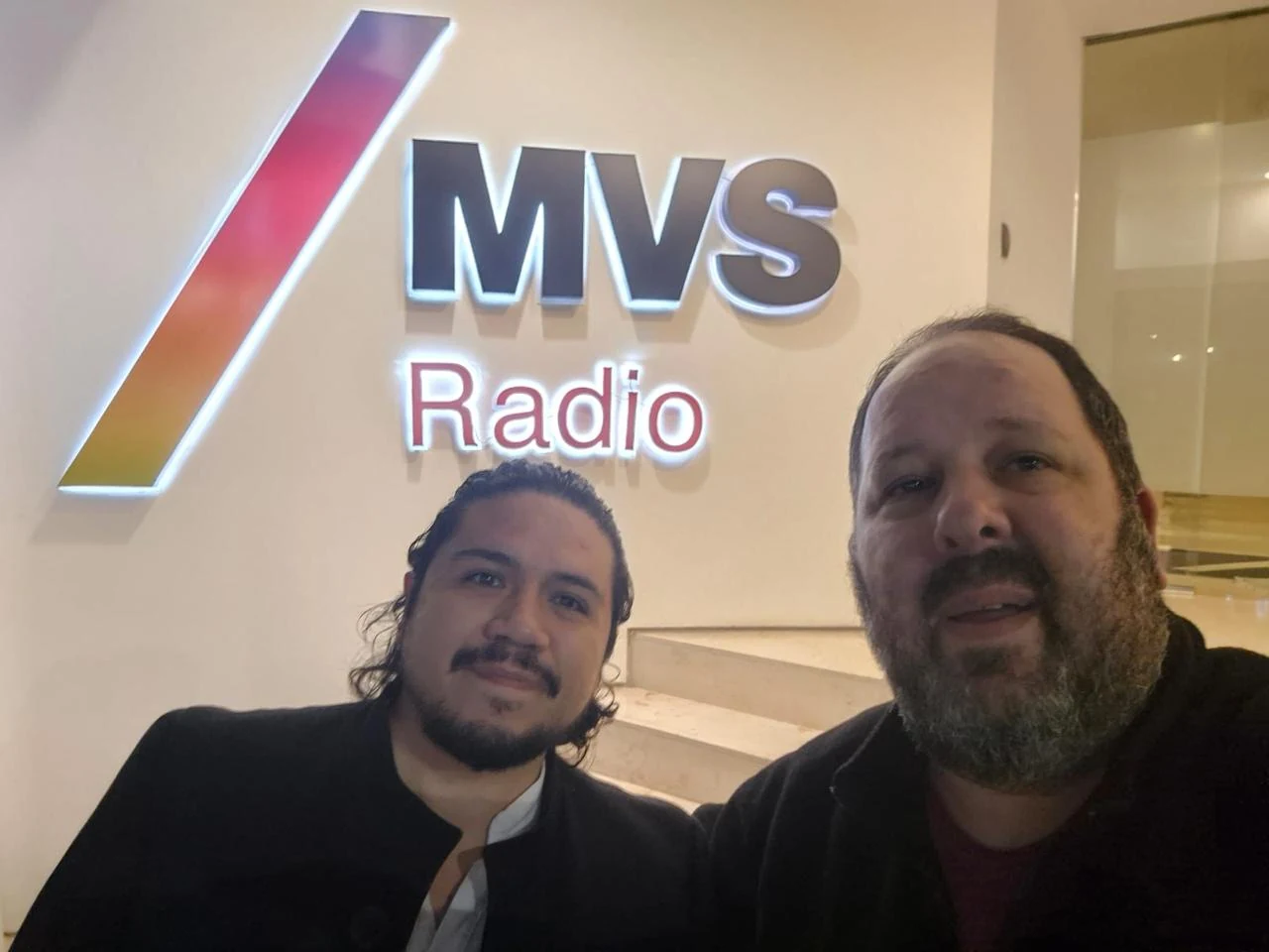 Alexis Soubran y Ron Oliver frente al logo de MVS Radio