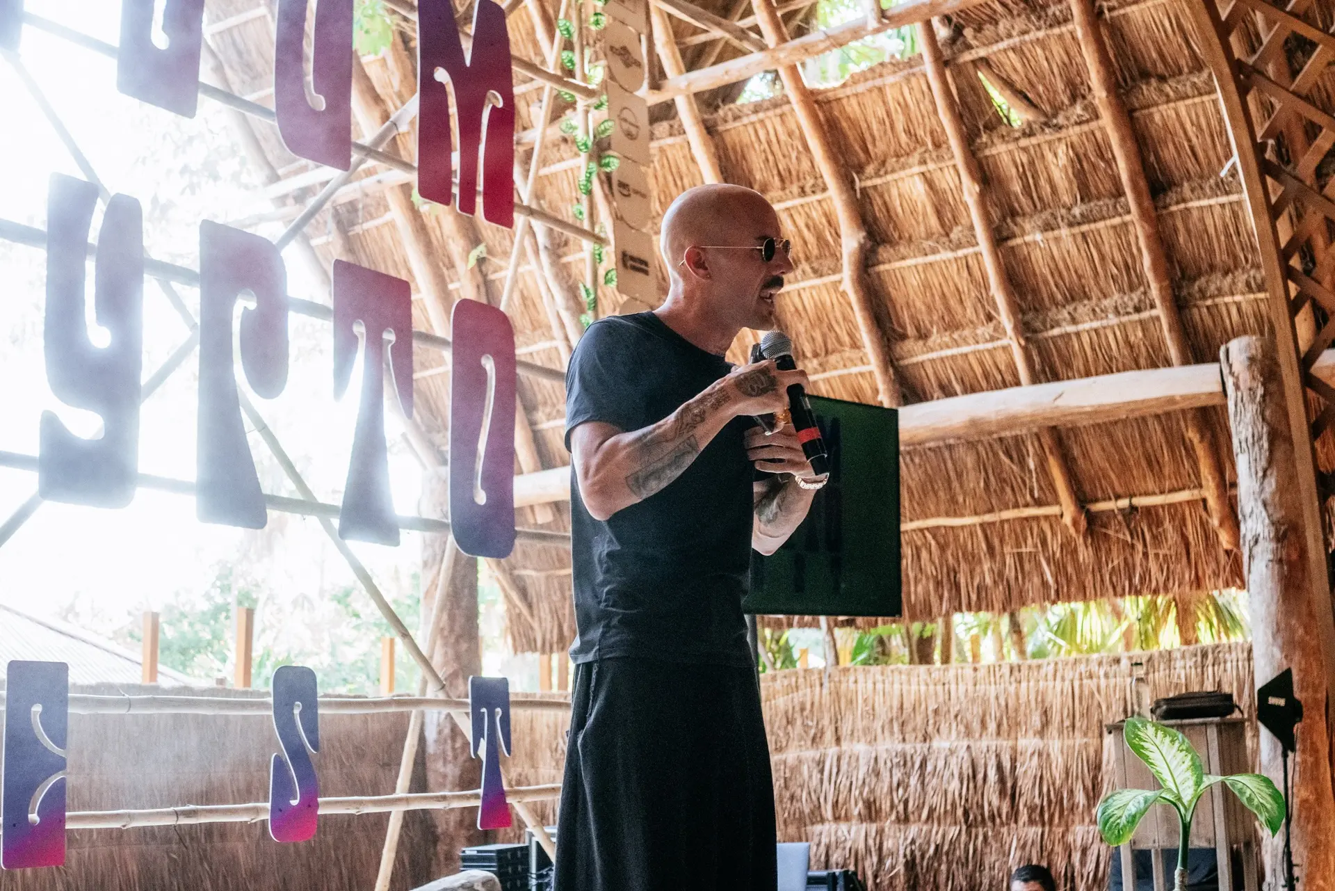Speaker presenting on an open-air jungle stage